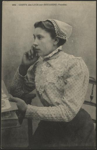 Les Lucs-sur-Boulogne. - Une jeune femme, en costume et coiffe, assise de profil accoudée à une table.