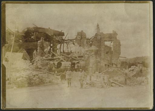 Deux soldats devant des bâtiments détruits par des bombardements dans les Ardennes.