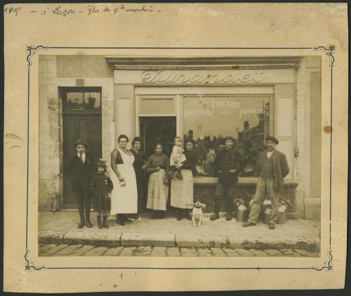 (194J10). Épicerie Durandet, rue des Grands Moulins, avec ses propriétaires et des clients devant la vitrine, 1915.